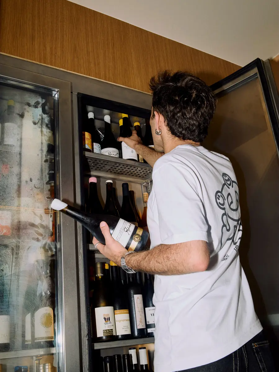 Un camarero saca una botella de vino de la nevera