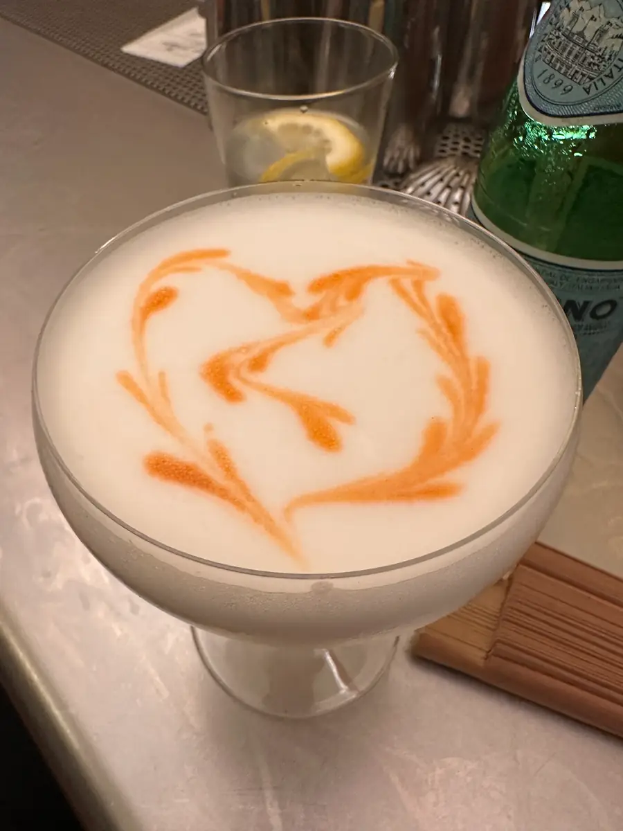 Un cóctel de la casa con espuma y un dibujo en naranja