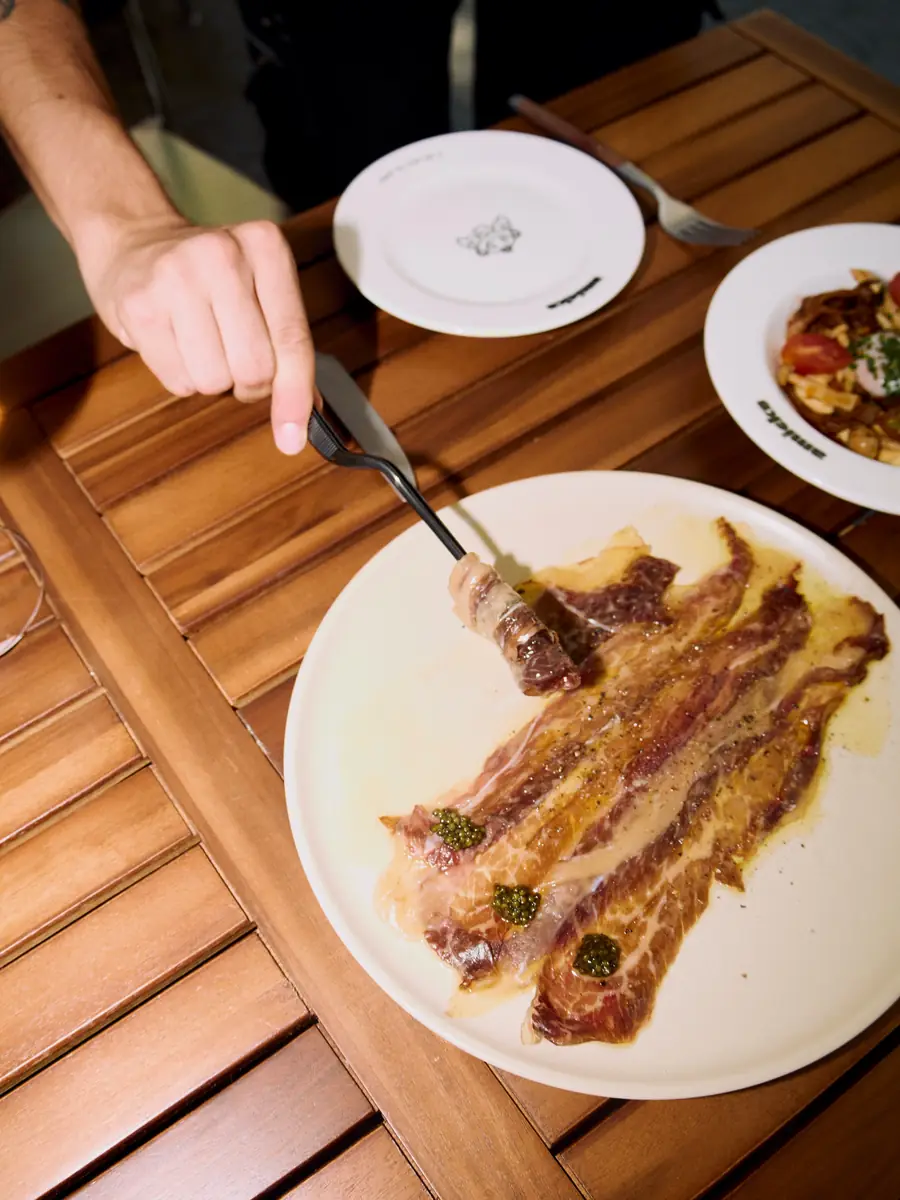 Picaña a la brasa cortada en lonchas; un comensal se sirve con el tenedor