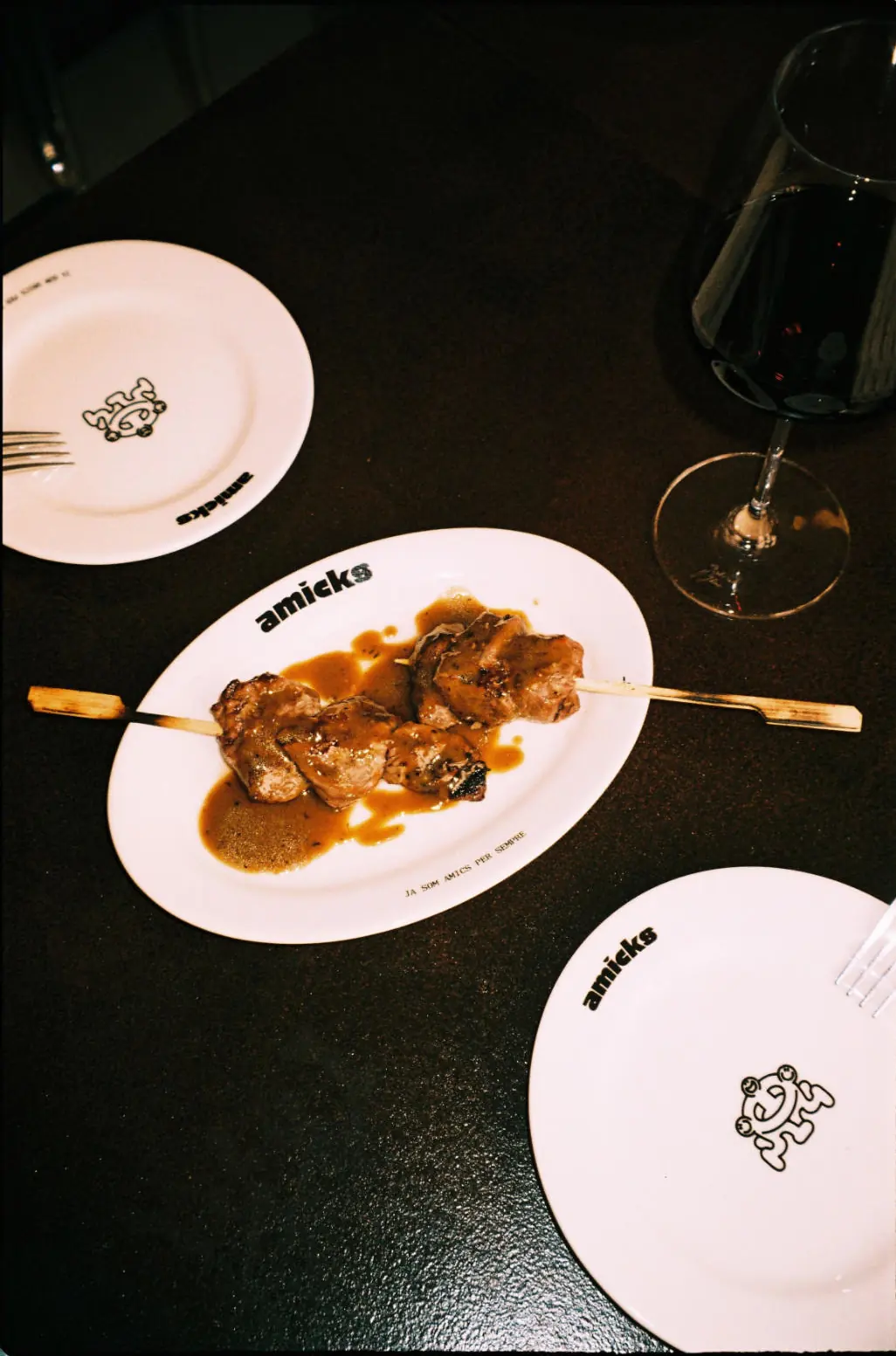 Una brocheta a la brasa con su salsa y una copa de vino tinto
